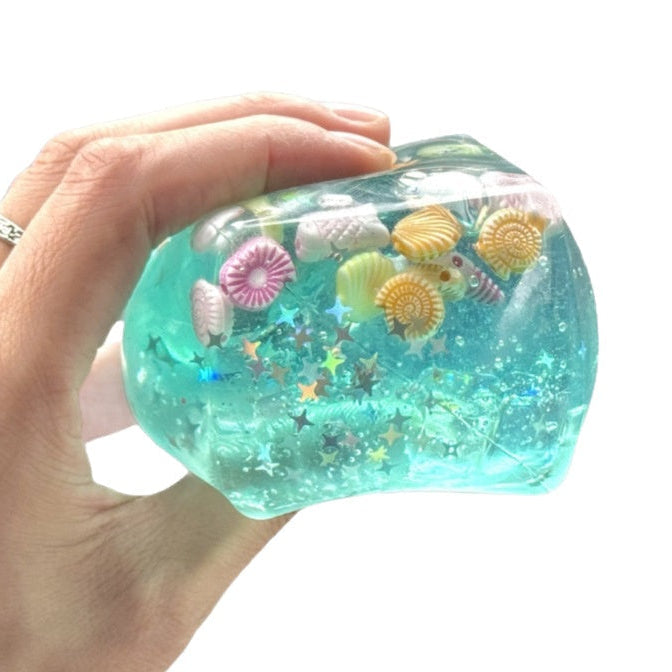 Turkos squishy-kub med snäckor som kläms i handen
